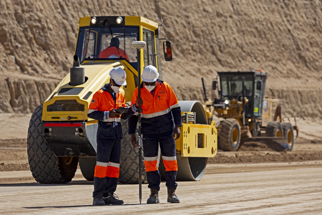 Drill rig silhouetted against sunrise in an open-pit mining operation