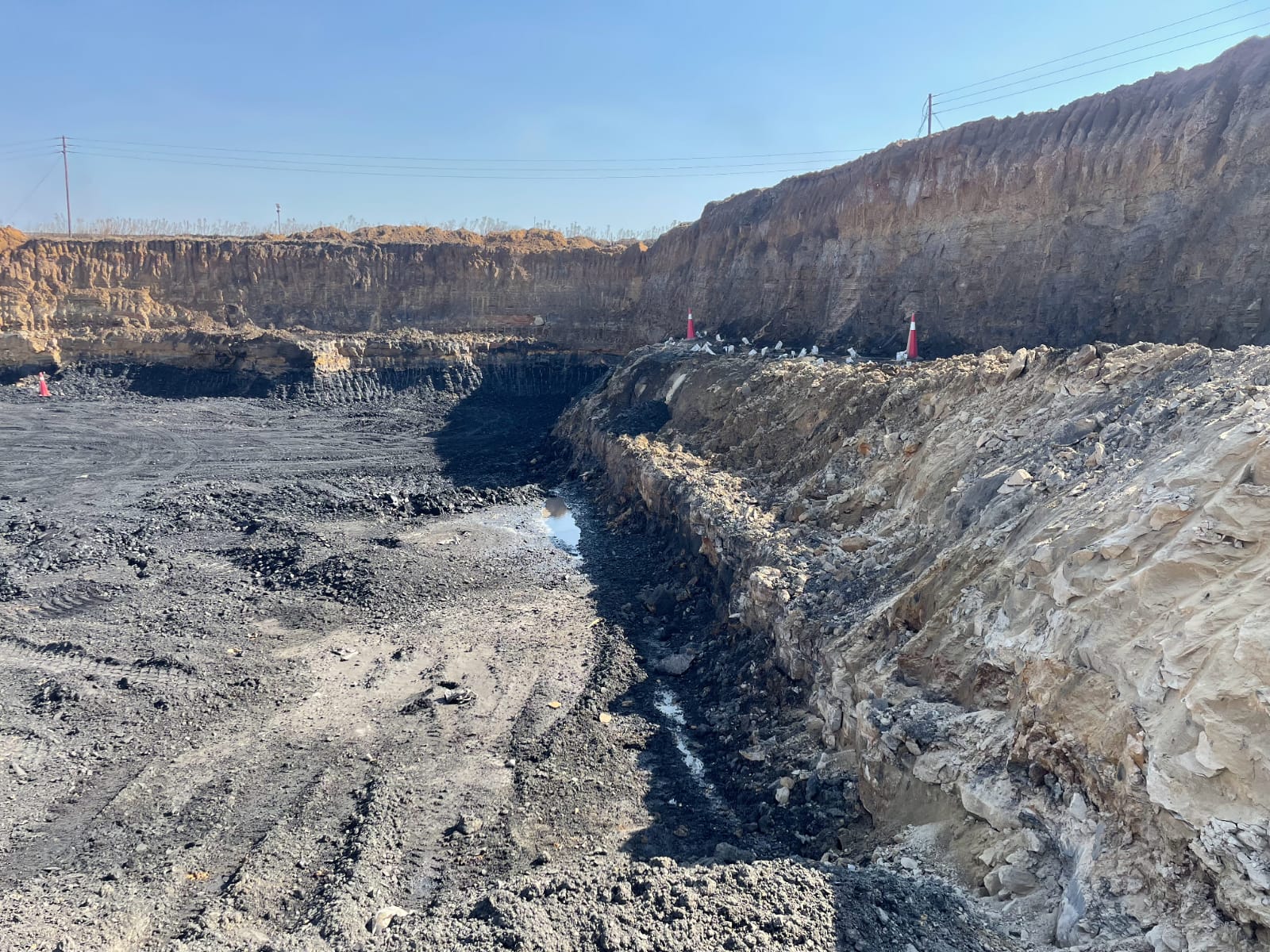 Working trench in an open-pit coal operation with demarcation cones on the bench