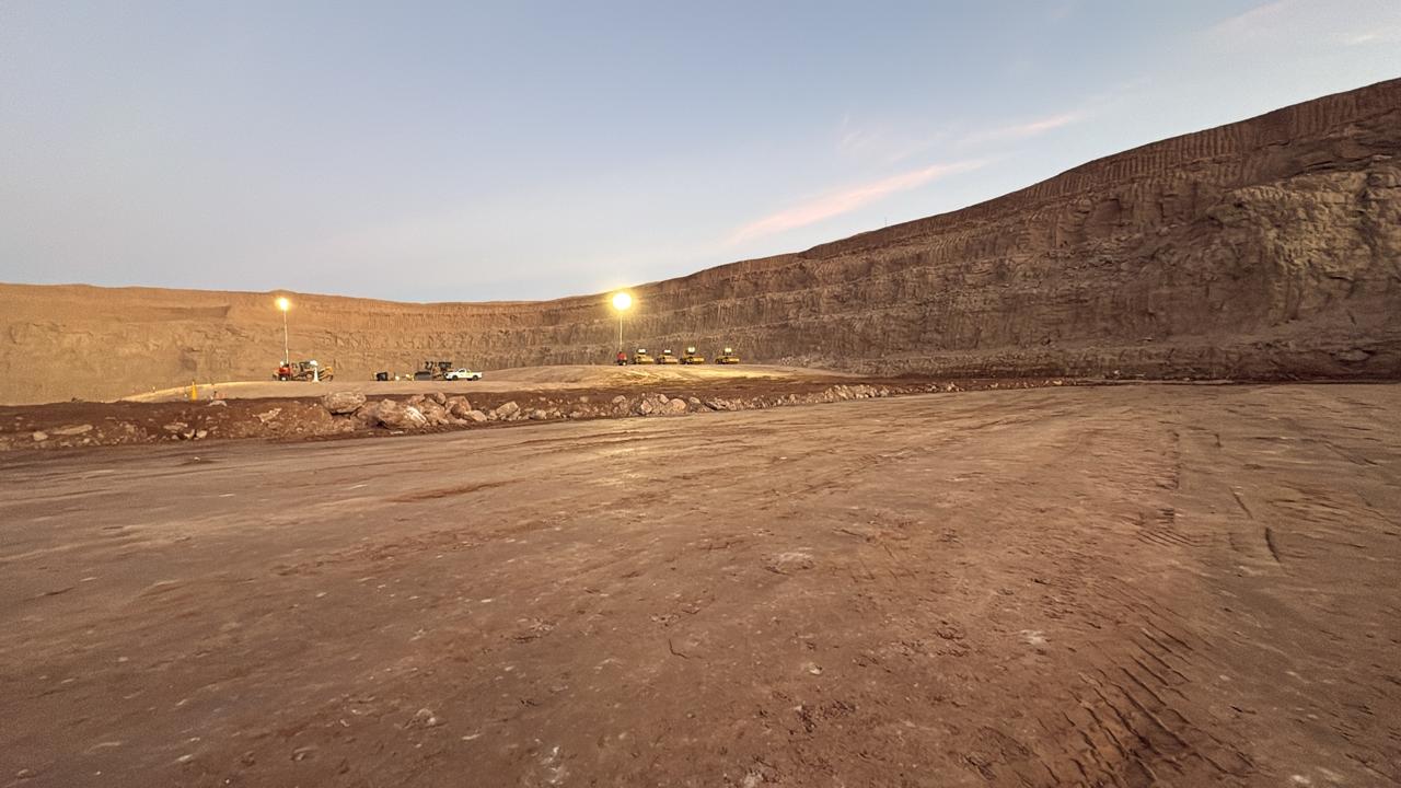 Open-pit excavation with water at the pit floor beneath layered benches